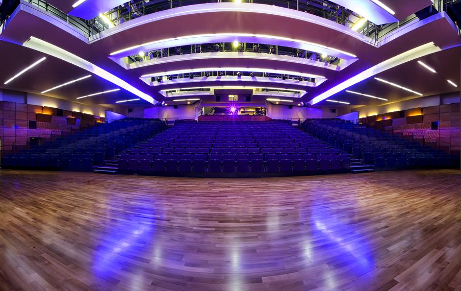 Raked seated auditoria with seating and high polished floor with ceiling track lighting.