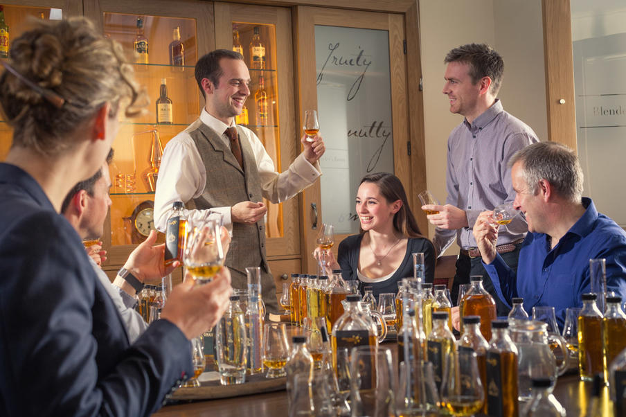 A group of people participating in a fun and educational blend your own whisky experience with a tutor.