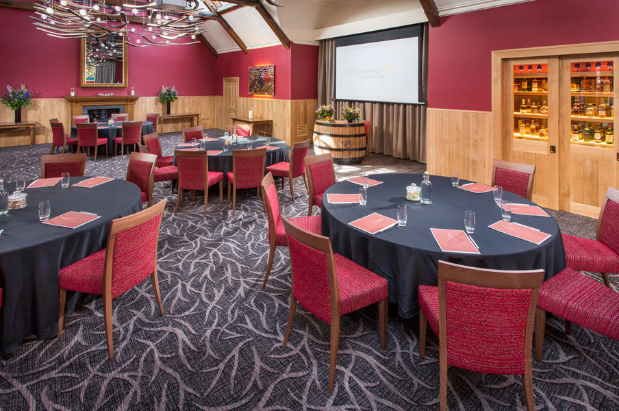 A large room set for delegates for a day conference, facing a screen