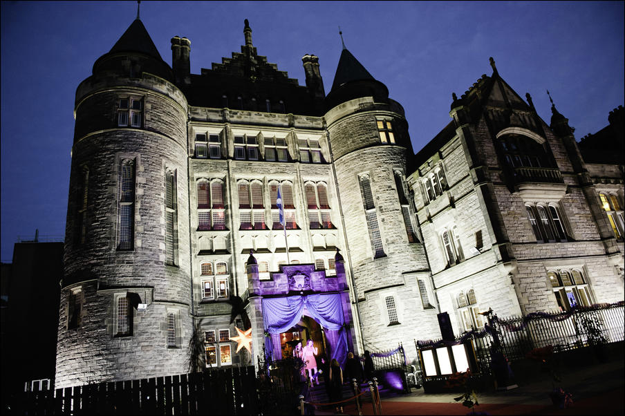 font facade of building showing turrets and arched windows with a red carpet for vip guests