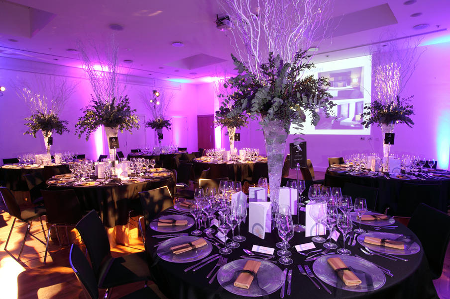 Wolfson Hall in Quincentenary Centre set for dinner in stunning purple and gold colours with a large silver centrepiece.