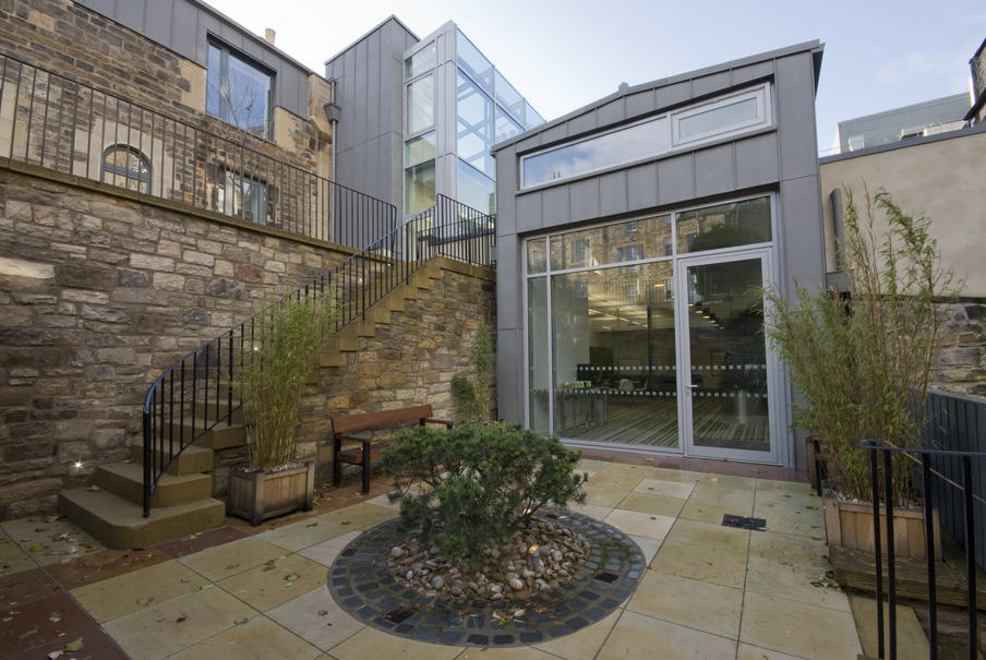 entrance to the meeting rooms from an enclosed courtyard with  flower bed and stone staircase leading to an upper patio area