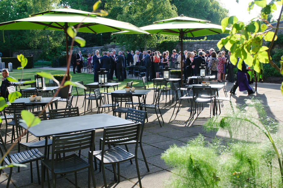 Guests enjoying drinks and canapés in the beautiful manicured gardens and terrace outside Café Modern One
