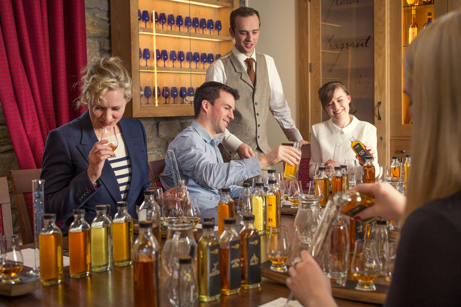 A group of people participating in a fun and educational blend your own whisky experience with a tutor.