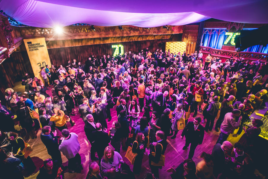 Drinks reception in large room with theme lighting.