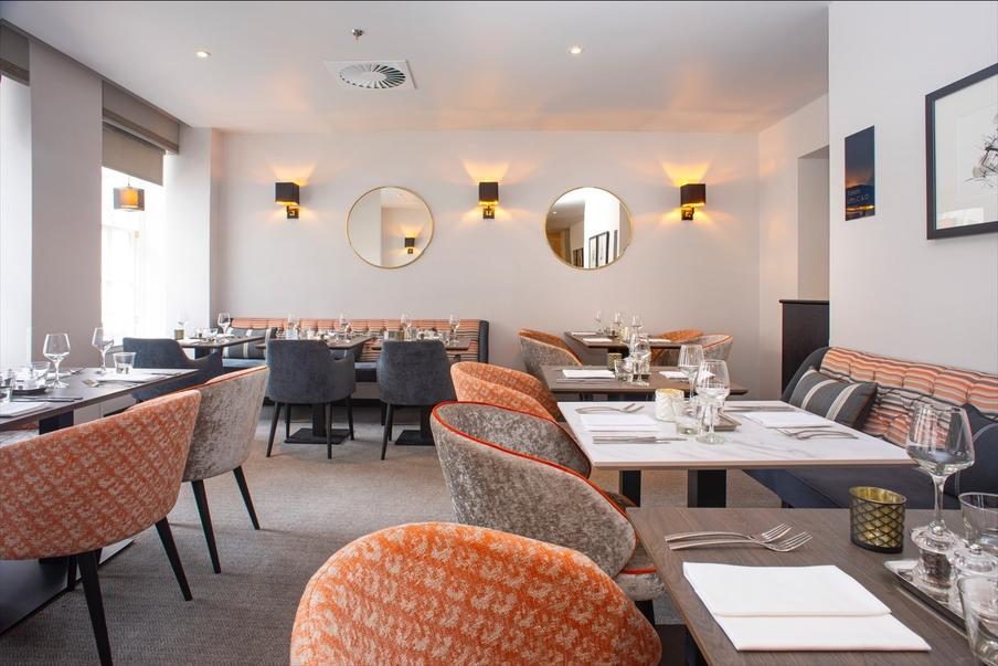 Restaurant decorated in warm orange and  grey tones with a choice of seating.