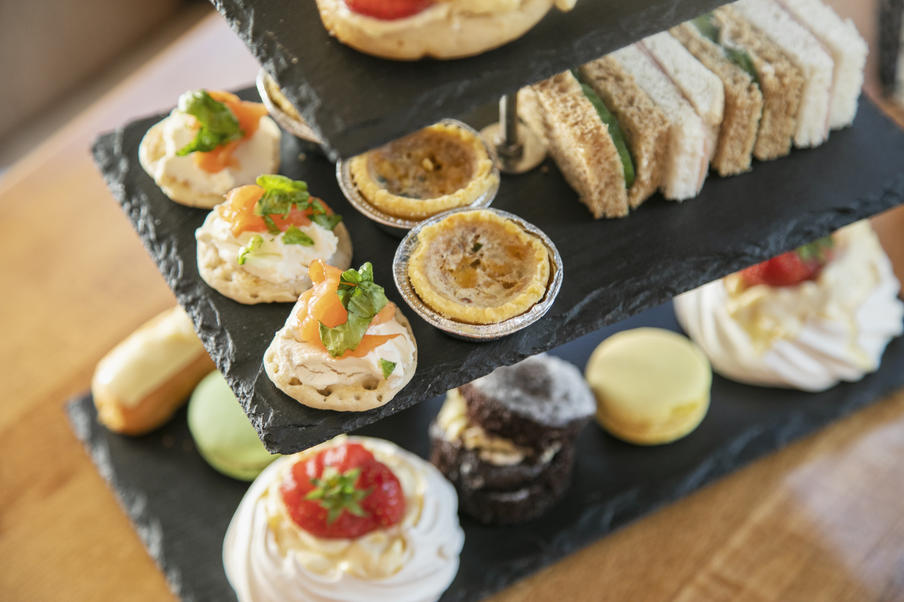 A cakestand displaying blinis, mini quiches, sandwiches and cakes