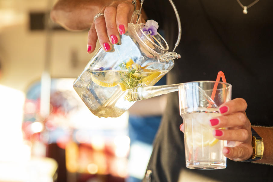 A gin cocktail being poured from a glass teapot