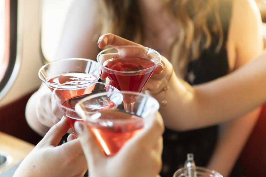 Three ladies clinking martini glasses of cosmopolitan cocktail