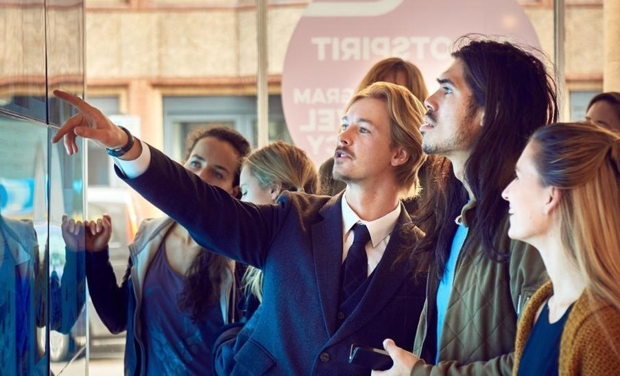 A tour guide explains a display board to guests