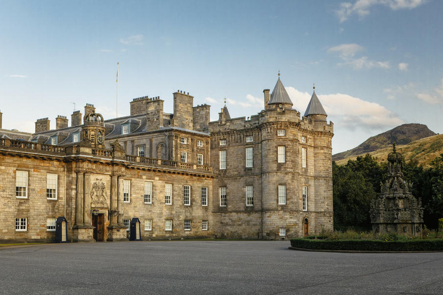 The Palace of Holyroodhouse during a summer evening with Arthur's Seat in the background.