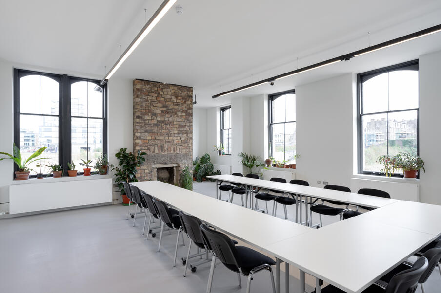 White room with large windows and a stone fireplace is set up as a boardroom