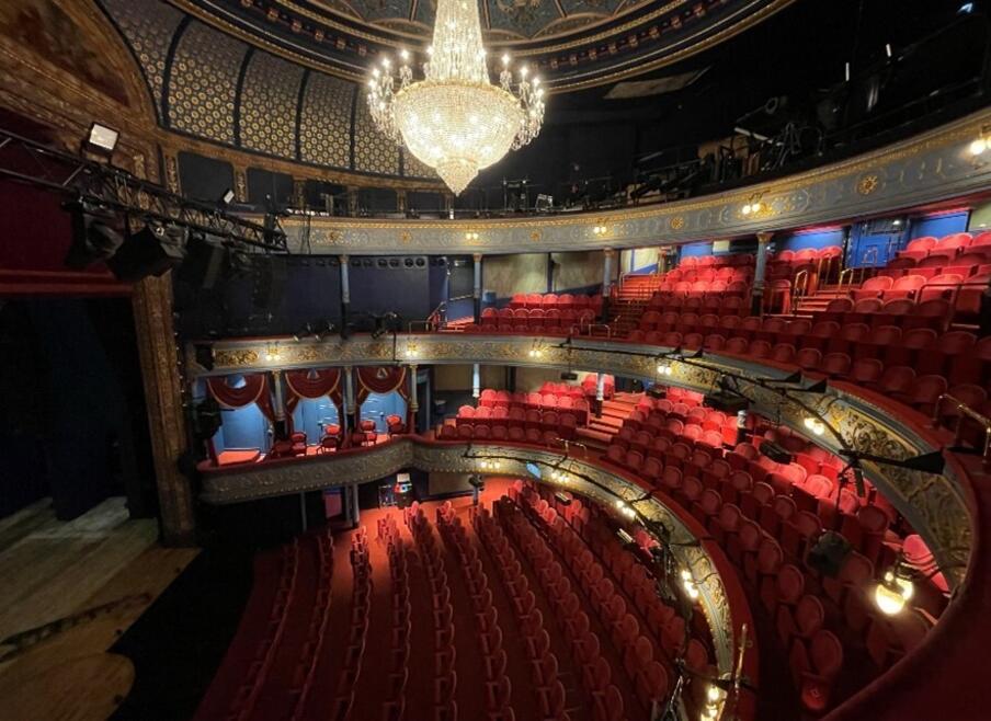 Dimly lit auditorium of The Lyceum. Image is taken from top level of seating tier, capturing red seats and chandelier.