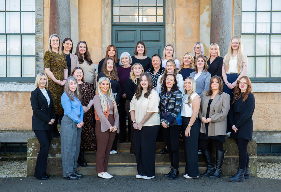 Fitwise all female team pose in front of the office front entrance.